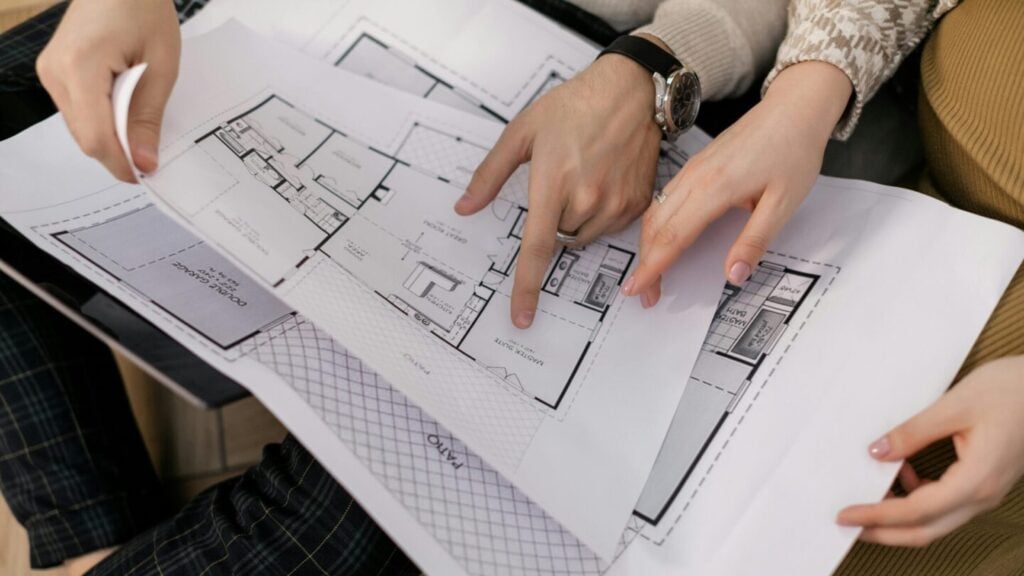 Two people reviewing architectural blueprints for a modular home construction